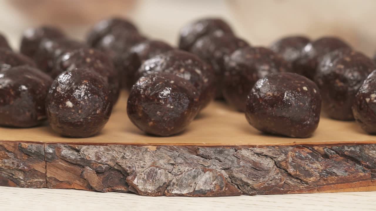 Left to the right shot of the amazingly tasty round chocolate candies. Woman's hand placing a just made candy onto the board. Homemade sweets recipe demonstration video
