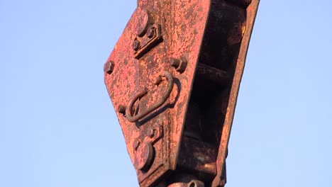 steel wires holding a heavy metal hook on a sunny day, clear sky background