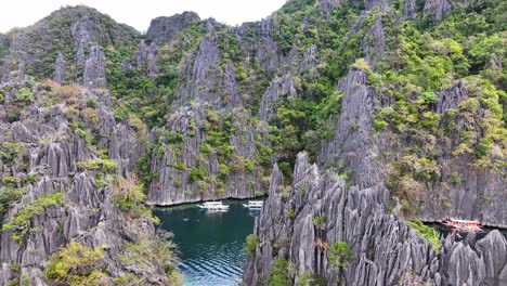 boats at twin lagoon surrounded by limestone cliffs in coron, palawan, philippines. - aerial shot