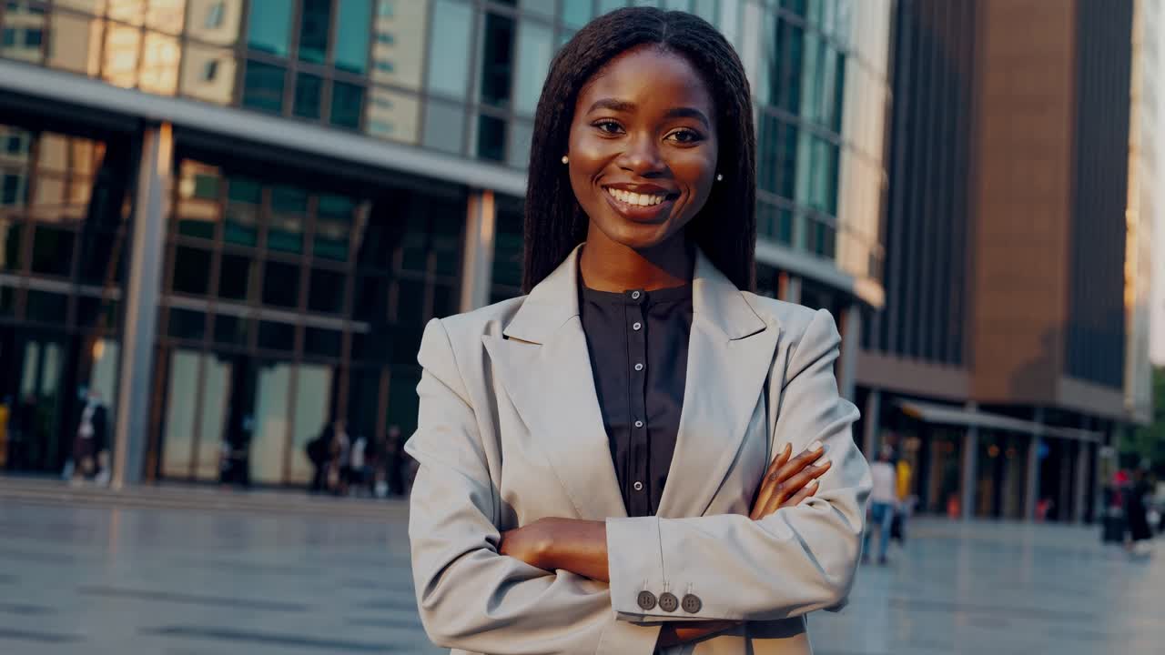 confiado gerente profesional afroamericano de pie con los brazos cruzados, irradiando éxito y liderazgo cerca del lugar de trabajo urbano moderno exterior