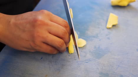 Cutting-ginger-into-small-pieces-on-blue-cutting-board-for-Asian-noodles-in-a-sushi-restaurant-by-a-chef