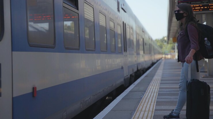 Woman in mask next to a passing train
