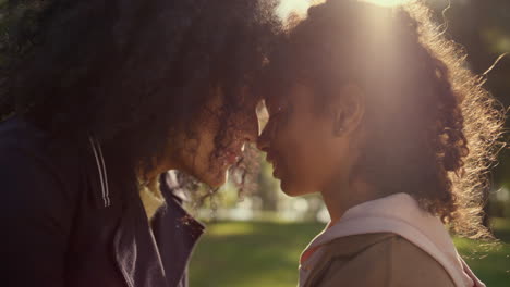 Loving-mother-touching-noses-with-dreamy-curly-daughter-golden-sunlight-closeup