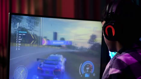 primer plano de un adolescente asiático emocionado que celebra la victoria y baila mientras juega a videojuegos en la computadora, jugando a un videojuego de carreras