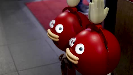 cartoonish red figures waving in a public space