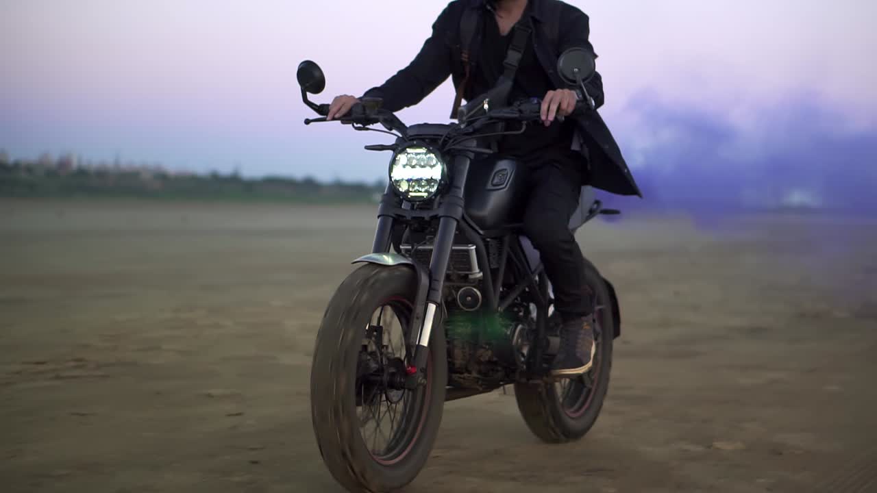 joven motociclista montando mientras el motor sopla humo de escape azul, holi