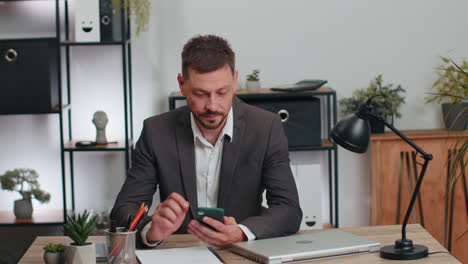 Businessman-in-suit-working-on-smartphone,-doing-manager-job,-typing-message-to-client,-office-room