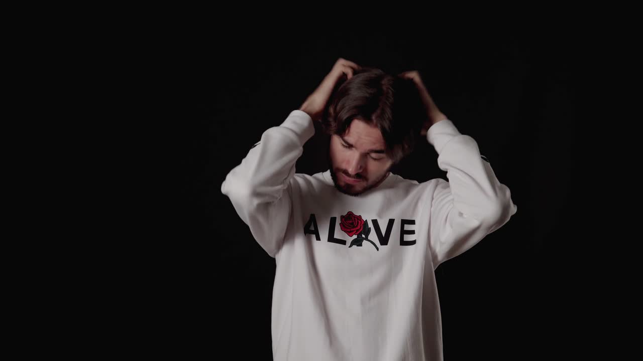 joven de moda jugando y alisando el cabello, amplio fondo negro