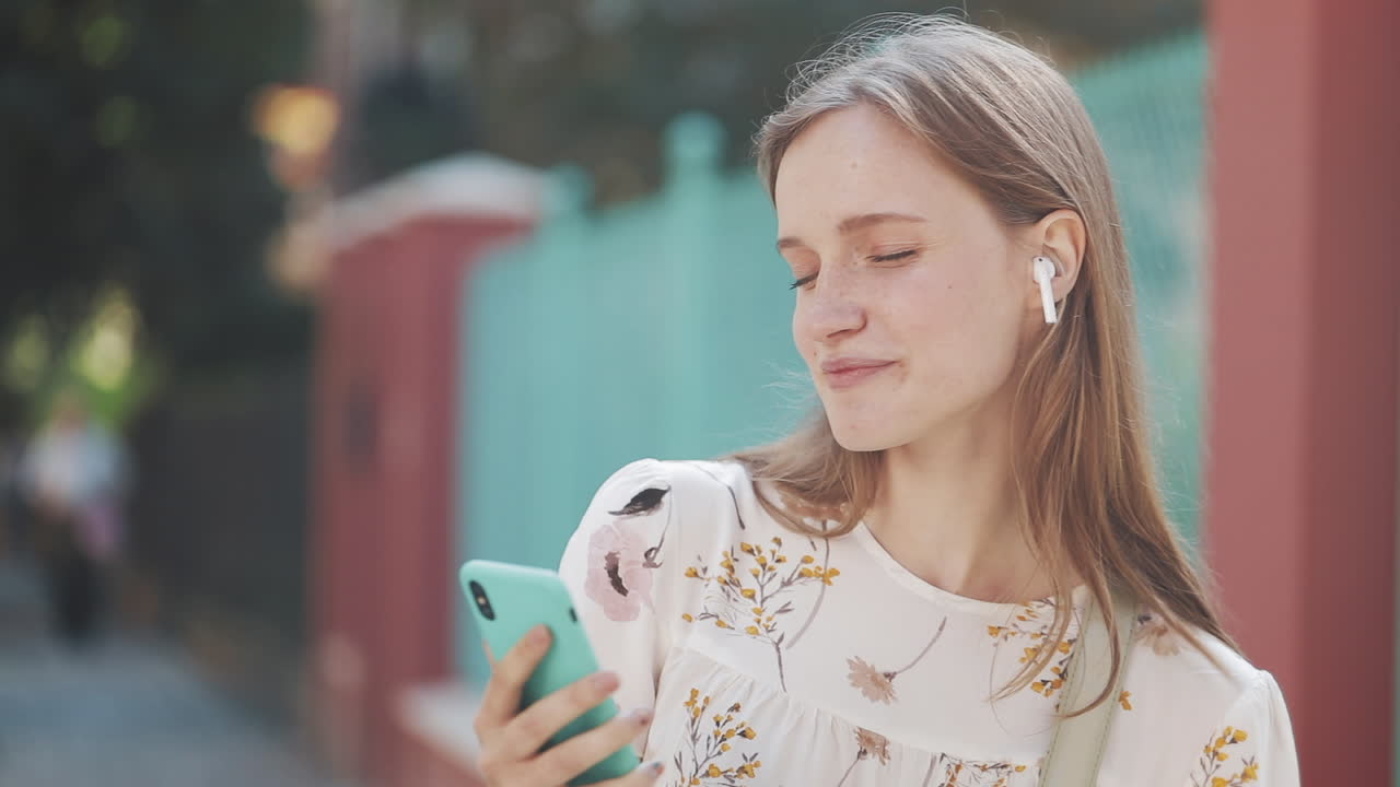 Giovane donna felice che ascolta musica sullo smartphone all'aperto