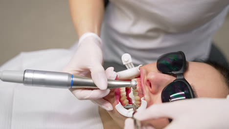 dental procedure to a woman. whitening beauty cosmetic procedure for teeth in dentistry studio. portrait of woman in protective glasses treating teeth.