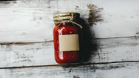 a jar of red sauce on a rustic wooden background