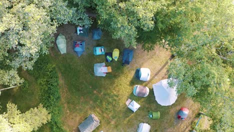 tents in the camping ground in a spring forest on a sunny day - aerial drone shot