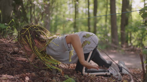 children in a summer camp hike crawls on the ground. training of passing obstacles by crawling on the ground. a girl tumbles in the forest on a camp assignment