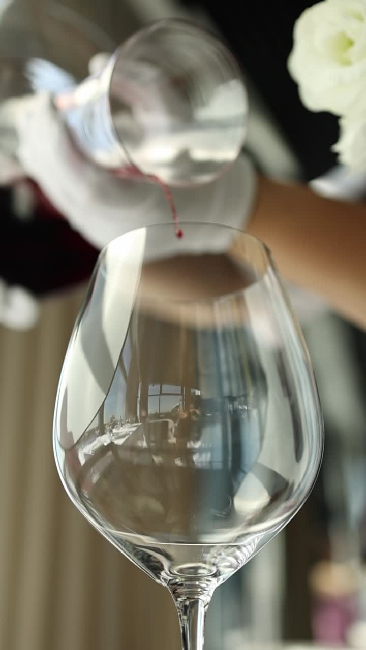 Hælder rødvin i et glas