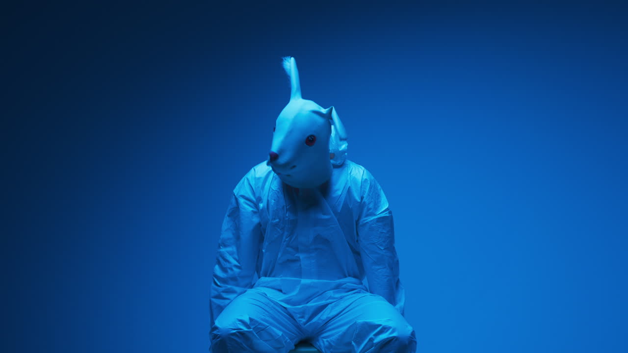 Persona che indossa una maschera da coniglio e una tuta protettiva sotto luce blu