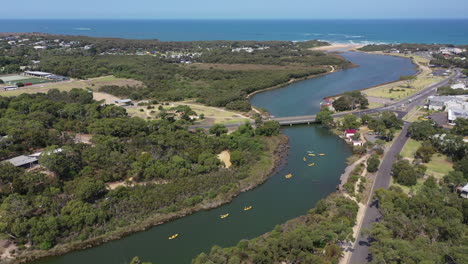 Orbiting-aerial:-Tandem-kayaks-paddle-Anglesea-River-near-ocean-coast