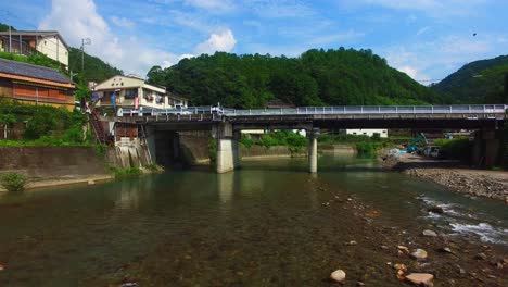 la perspectiva del dron revela un encantador pueblo japonés, acercándose al puente sobre un río tranquilo.