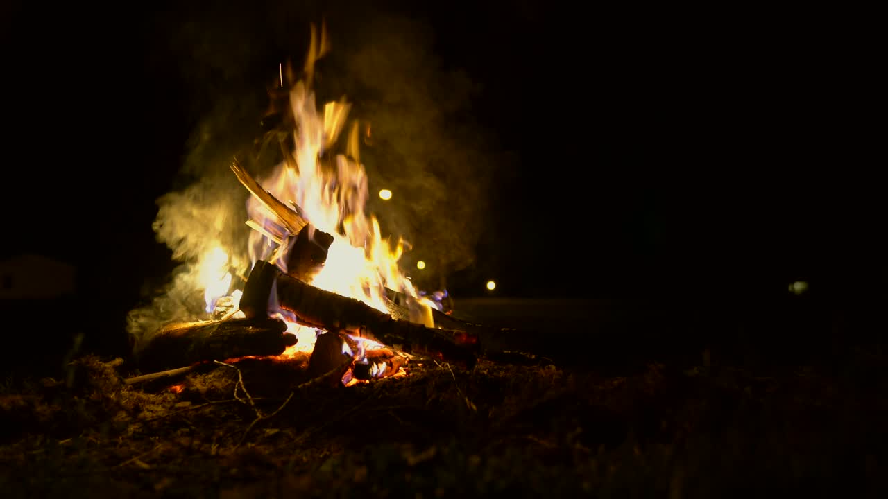 disparo estático de un fuego de campamento por la noche como un pedazo de madera se quema lentamente y cae en el fuego