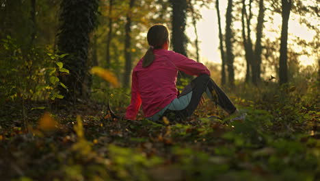 woman sitting peacefully in a forest during golden hour