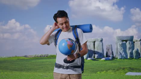 confused traveler looking at a globe near stonehenge