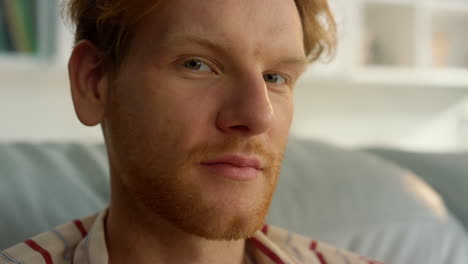 pensive guy looking camera closeup. handsome ginger man resting at cozy home.