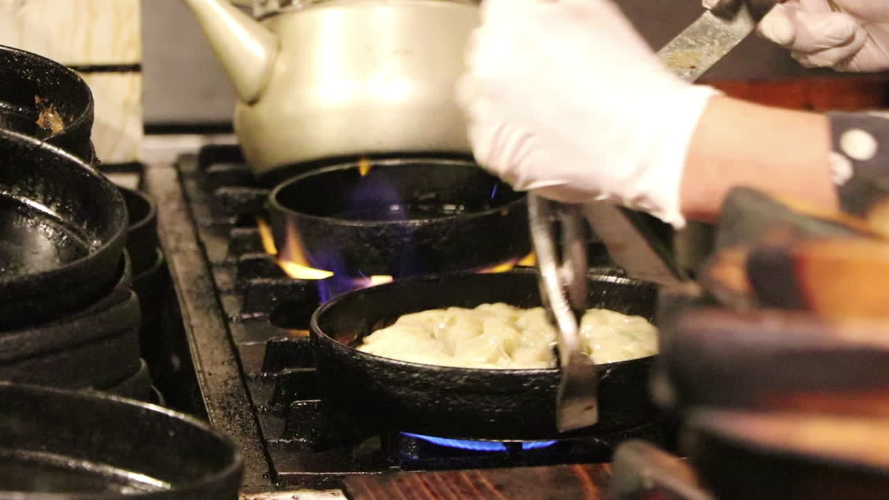 Close up of someone cooking Gyoza in a pan