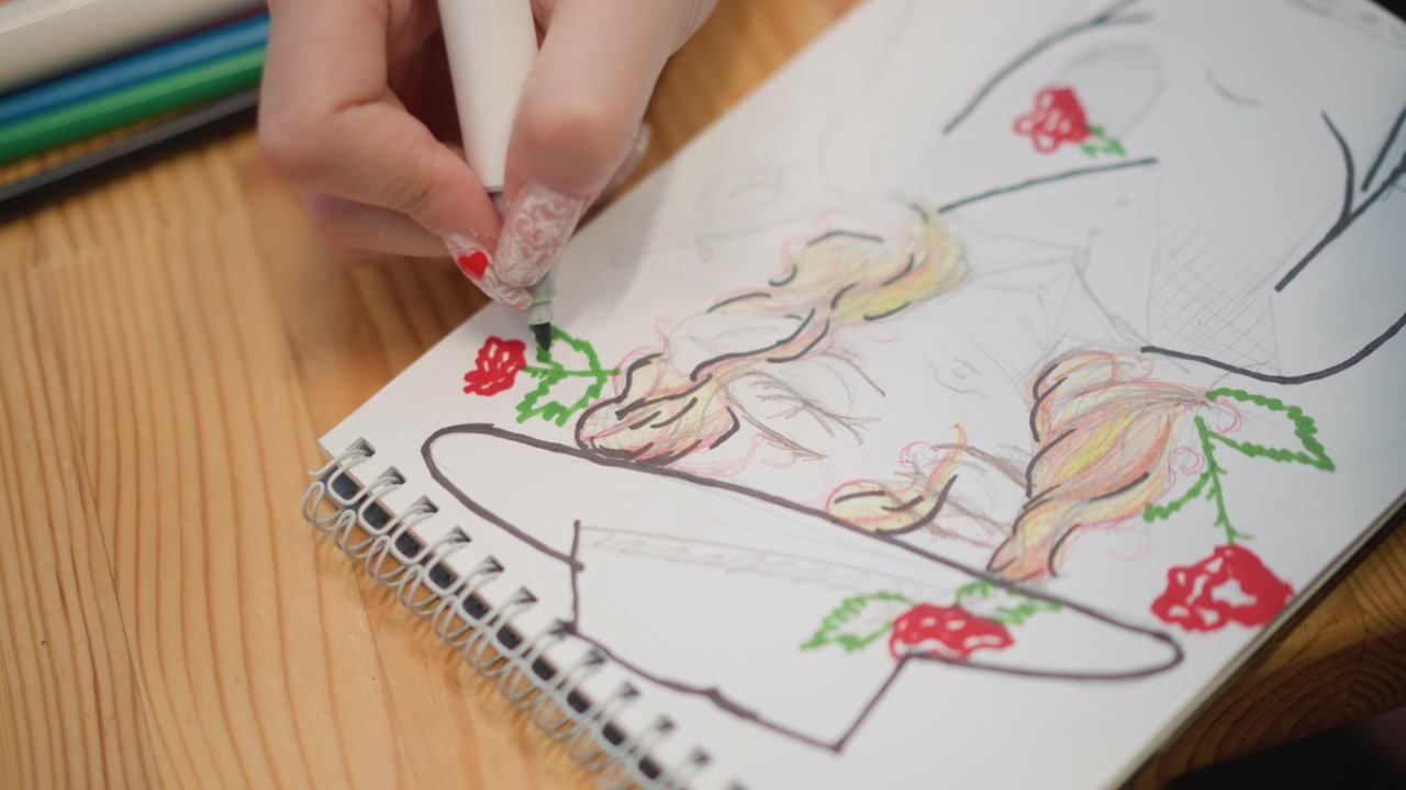 Close-up sudut tinggi menunjukkan tangan menggunakan pensil warna berujung putih untuk mewarnai daun hijau di samping stroberi cerah pada ilustrasi buku sketsa yang sebagian sudah diwarnai, mengungkapkan karya kreatif yang teliti