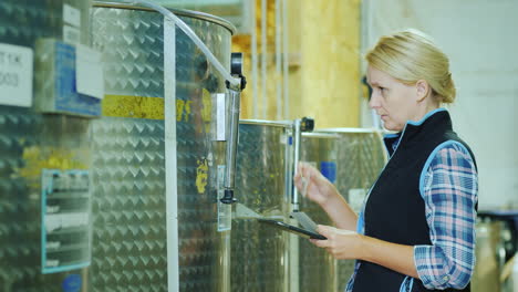 a woman with a tablet works near the food tank checks the tag on the barrel quality control in food