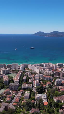 vertical drone shot, cannes france, city waterfront hotels and yachts in mediterranean sea on hot summer day