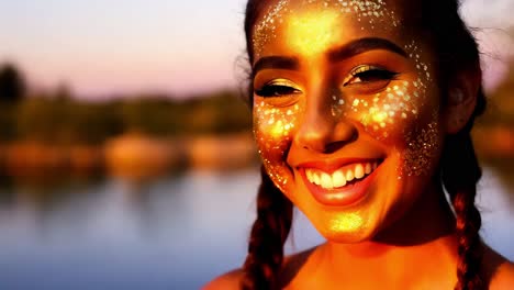 smiling woman with gold glitter face paint