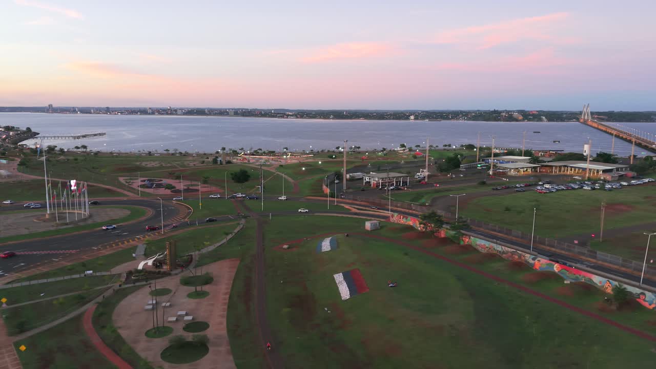 Dawn coastal Posadas cityscape in aerial view with long walkway and red-soiled park area, Misiones, Argentina.