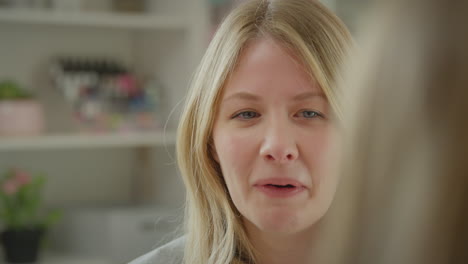 over the shoulder view of mother talking with teenage daughter wearing pyjamas sitting on bed  in bedroom - shot in slow motion