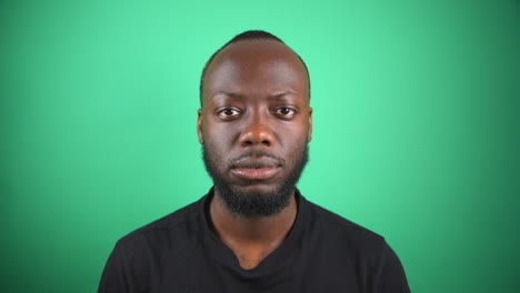 hombre negro mirando fijamente a la cámara con la cara en blanco con fondo de pantalla verde