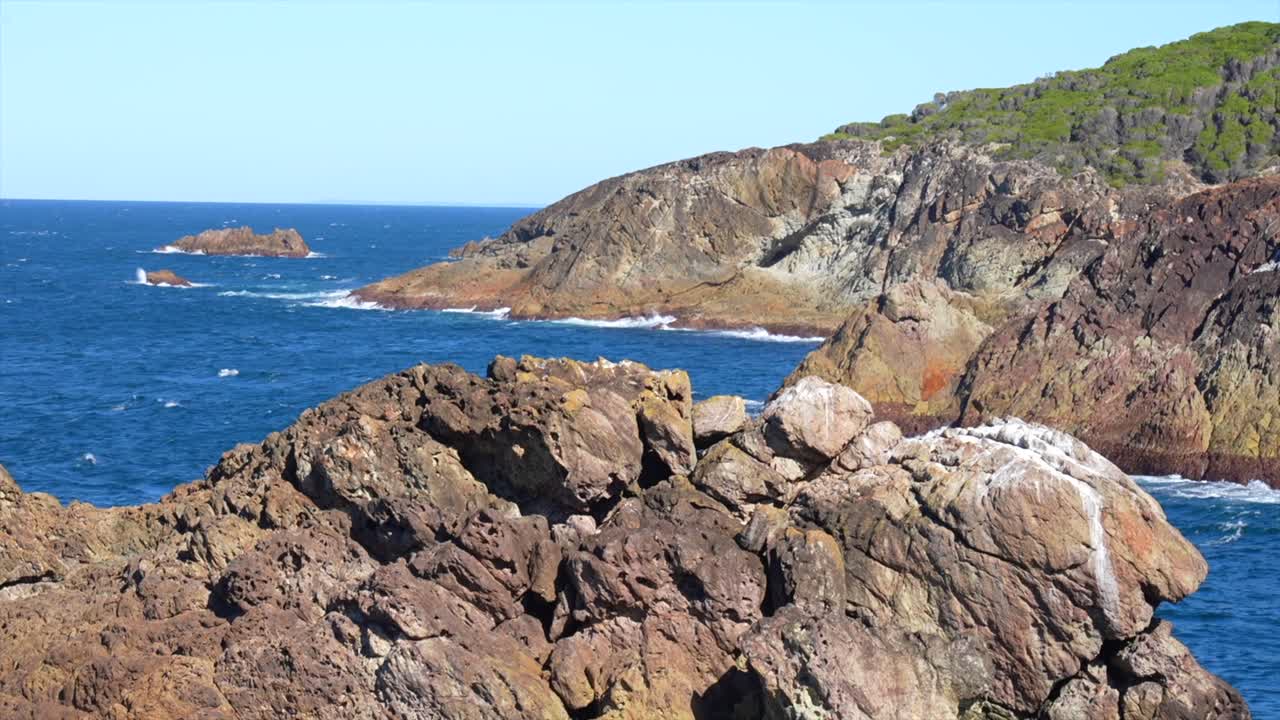 Promontorio roccioso in primo piano con scogliere costiere e l'oceano oltre, Tathra, Nuovo Galles del Sud, Australia.