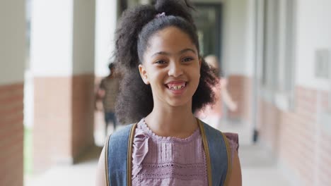 video of happy biracial girl standing at school corridor