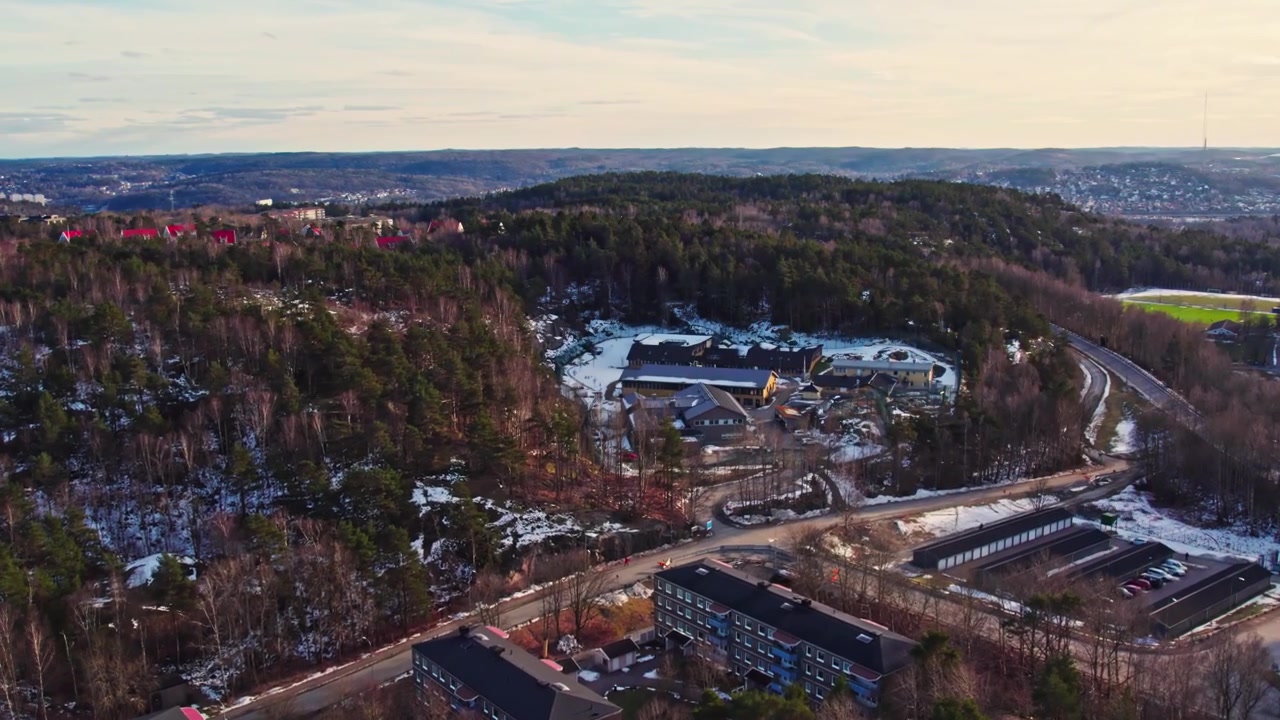 Dronen ilmakuva turvallisesta nuorten asuinkodista, jota ympäröivät metsätiet ja talvinen maisema, kouluikäisille pojille Bergsjössä, Göteborgissa, Ruotsissa