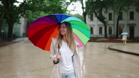 portrait of a woman walking by city street with multi-colored umbrella