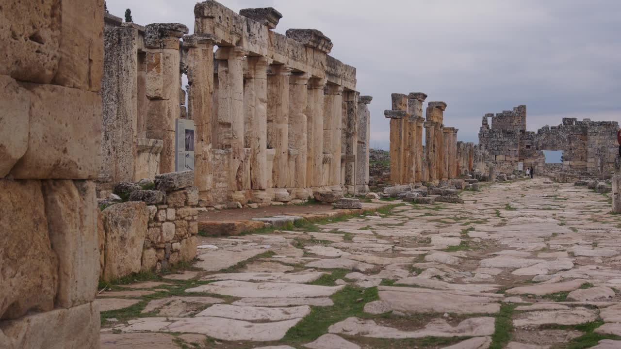 las ruinas de edificios y pilares a lo largo de un camino en hierápolis
