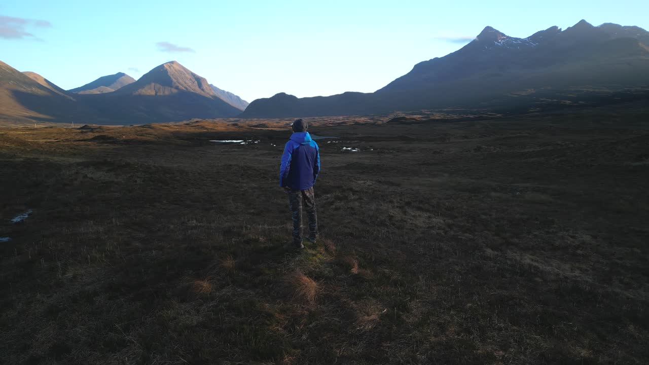montañas cuillin iluminadas por la luz del amanecer mientras el excursionista admira la vista