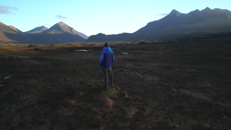cuillin mountains lit by dawn light while hiker admires the view