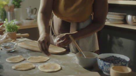 close-up of hands sprinkling sugar on dough in a kitchen