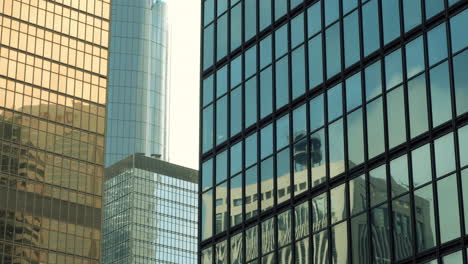 modern walls are made of glass and steel with reflections of buildings and blue sky