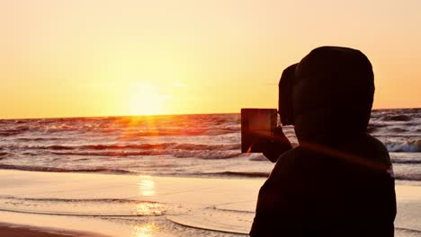 windy evening at sea as person records sunset glow near water on latvian coast