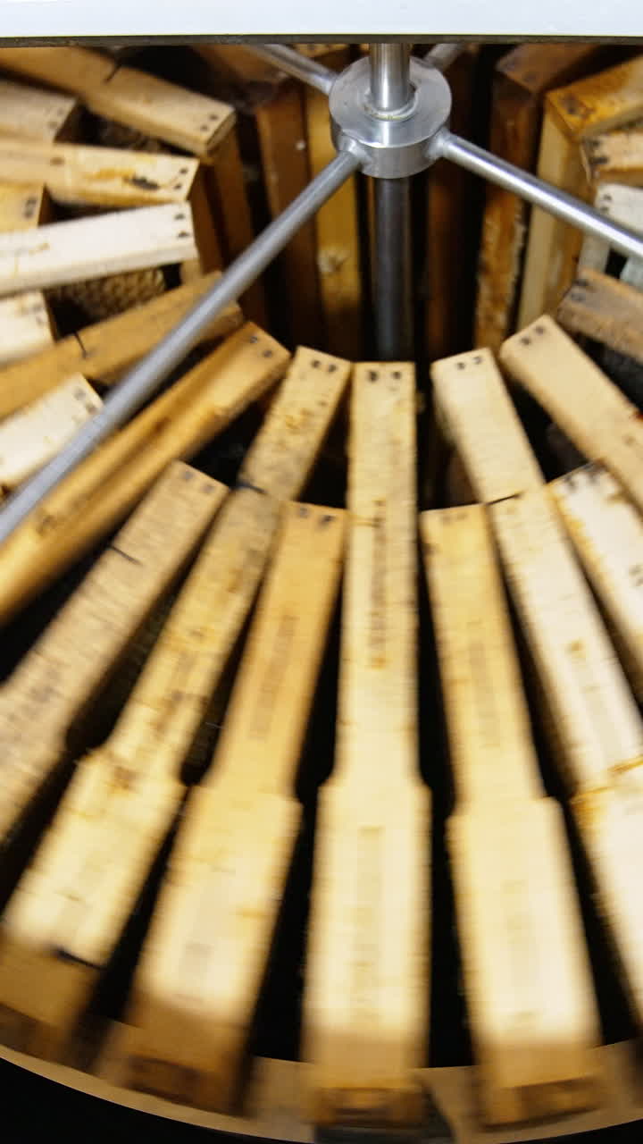 Centrifuge inside a metal barrel rotating and spinning honey frames. Extracting healthy product in special device. Vertical video