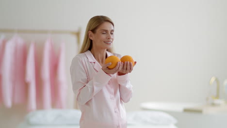 woman smelling oranges in pajamas