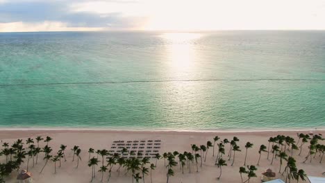 Tropical-beach-and-resort-in-sunrise,-luxury-resort-with-sand-beach,-palm-trees-and-pool-area-in-the-Dominican-Republic,-beautiful-getaway-oasis,-aerial-view