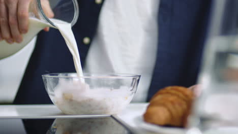 closeup man hand pouring milk into glass bowl with cornflakes in slow motion.