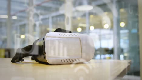 Multiple-digital-icons-against-vr-headset-on-a-table-at-office