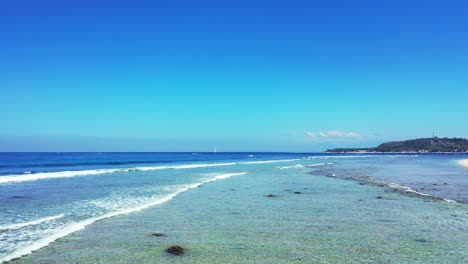 white waves washing rocky sea bottom on shore of tropical island, beautiful seascape with blue sea and sky on a bright morning in indonesia