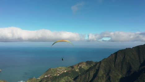 aerial of paraglider soaring through air above scenic mountains of madeira